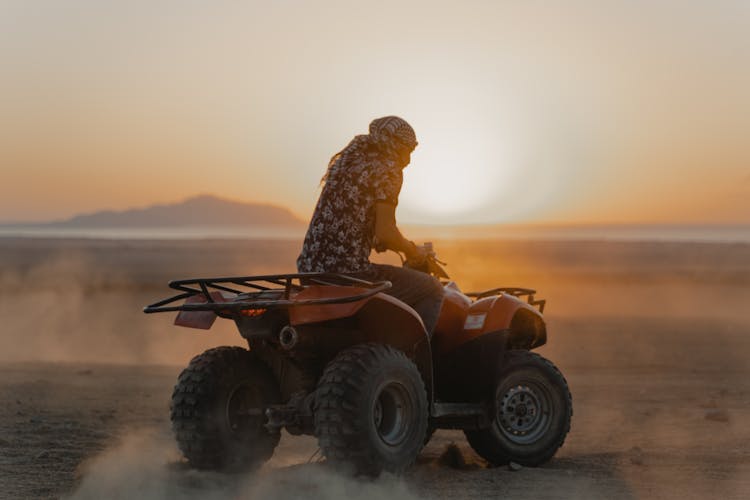 Person Riding An Atv On Brown Sand