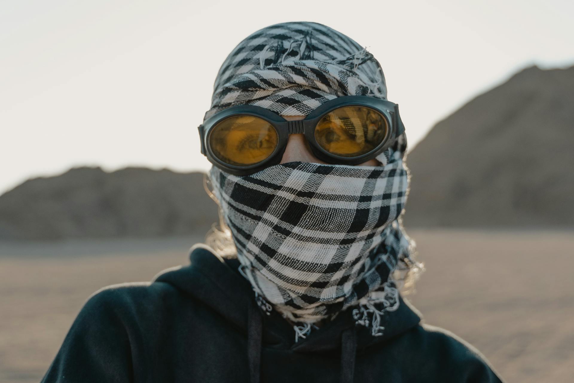 A person in a desert wearing goggles and a headscarf for protection from the elements.