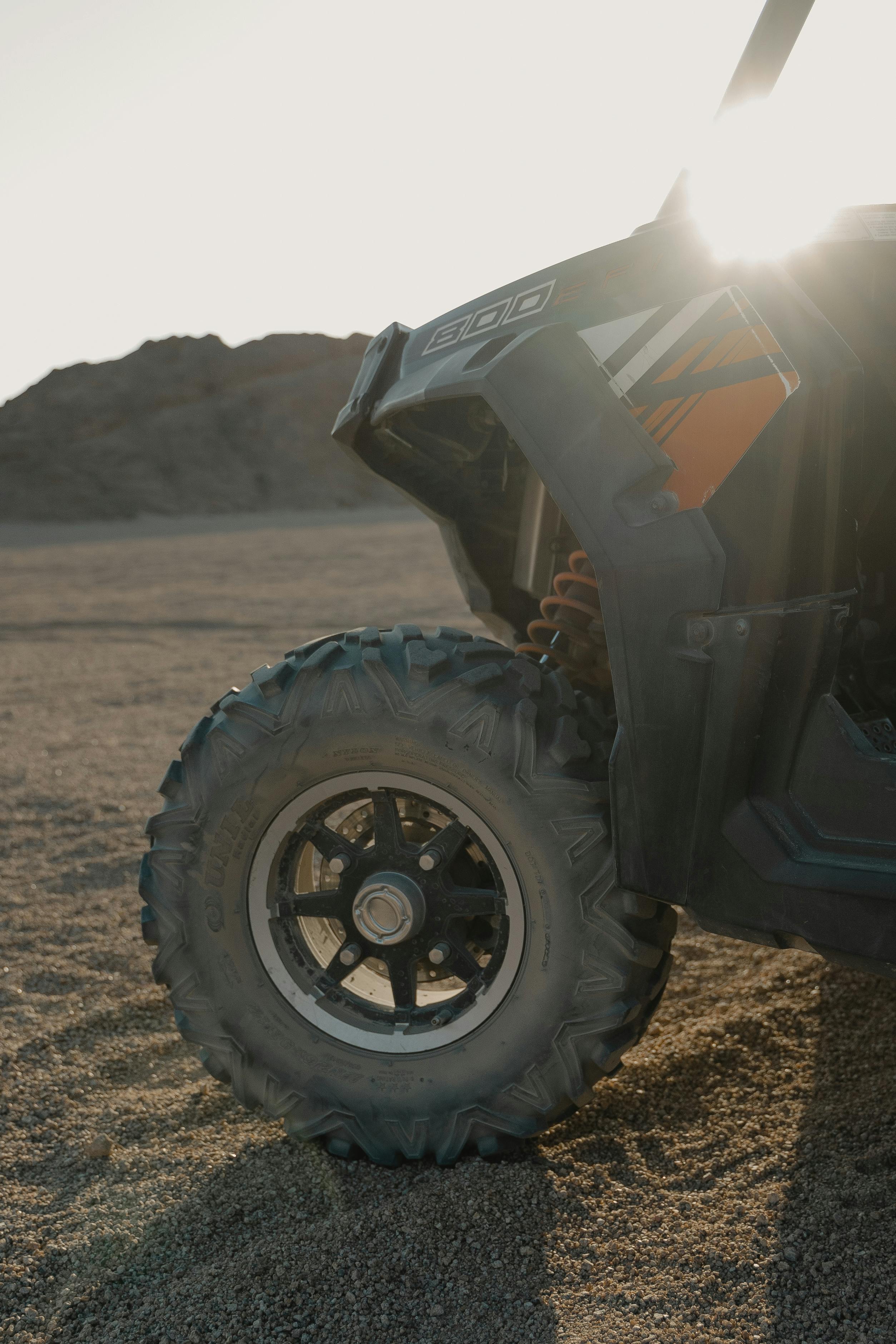 Close-up of an ATV wheel in the desert, backlit by the sun.