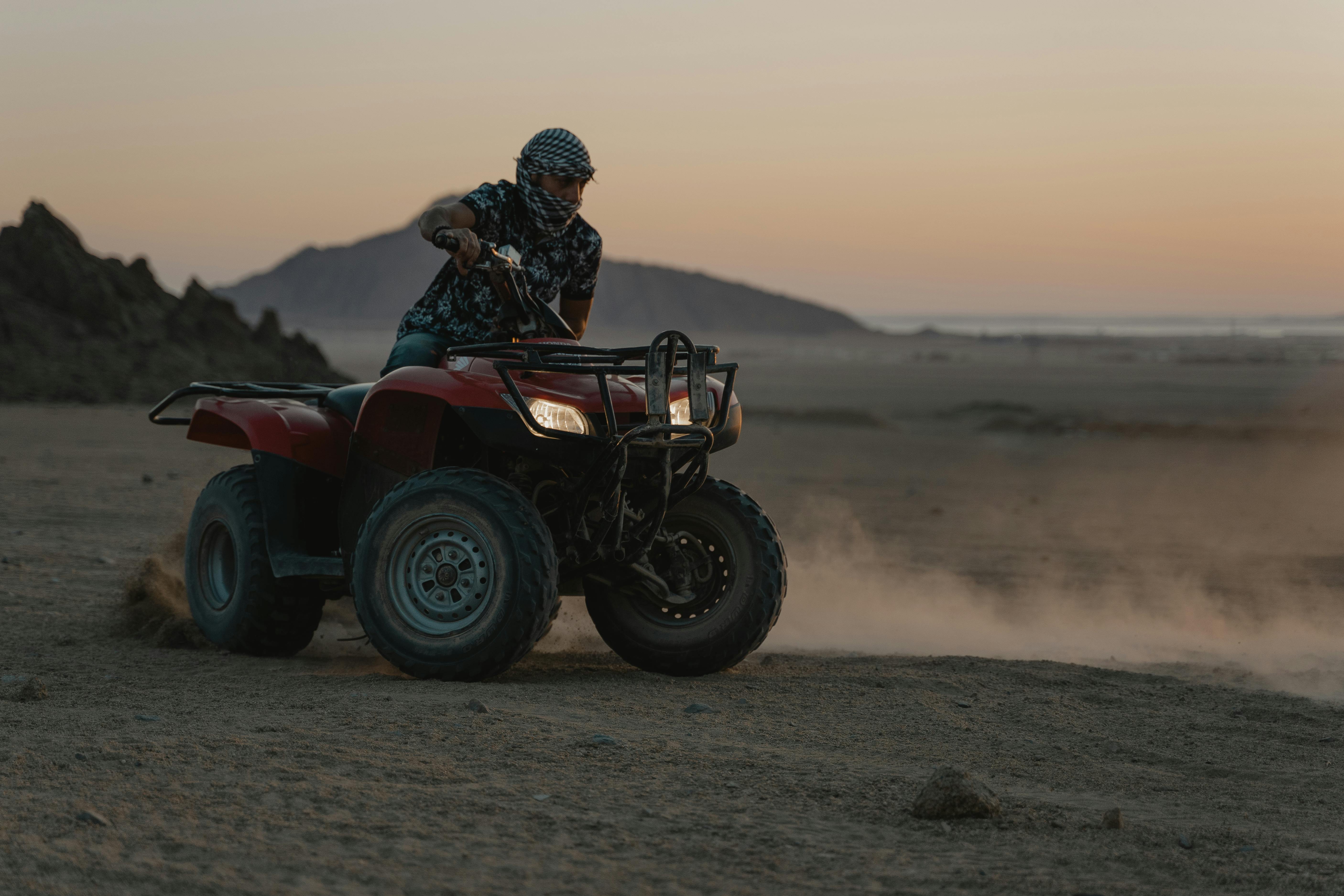 person riding an atv drifting on sand