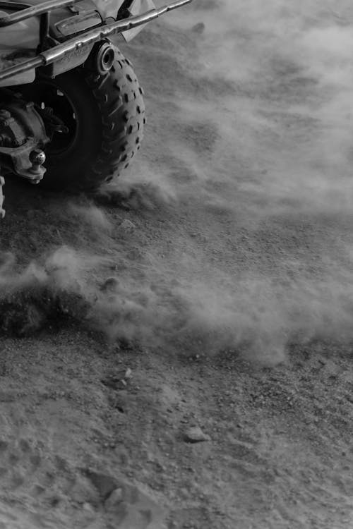 Grayscale Photo of Wheels Drifting on Sand 