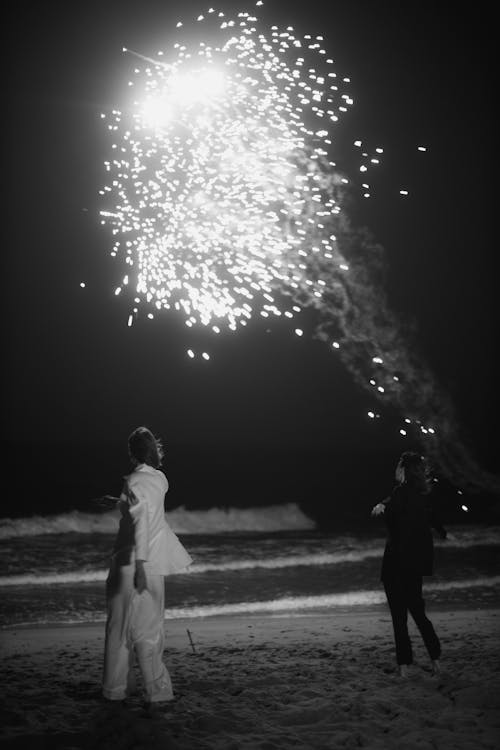 Grayscale Photo of People at the Beach Enjoying the Fireworks 