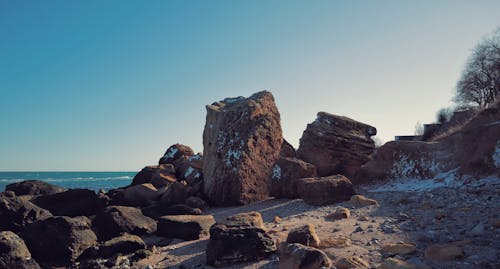 Free Rocky formations on sandy seashore in sunlight Stock Photo