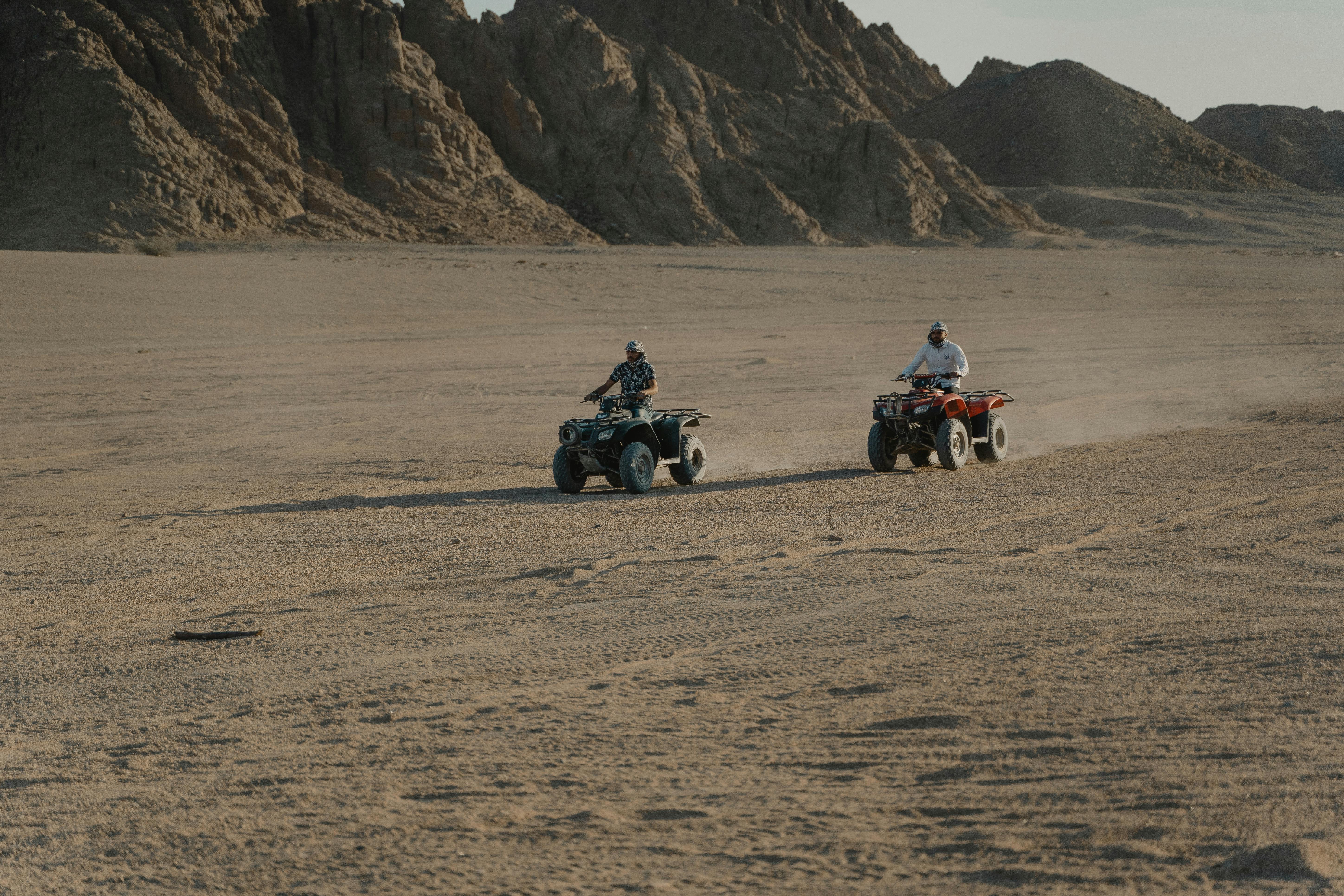Two people ride ATVs across a dramatic desert landscape, evoking a sense of adventure.