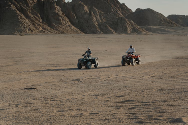 People Riding Atvs On Brown Sand