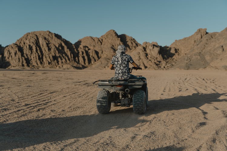 Back View Of Person Riding An Atv On Brown Sand