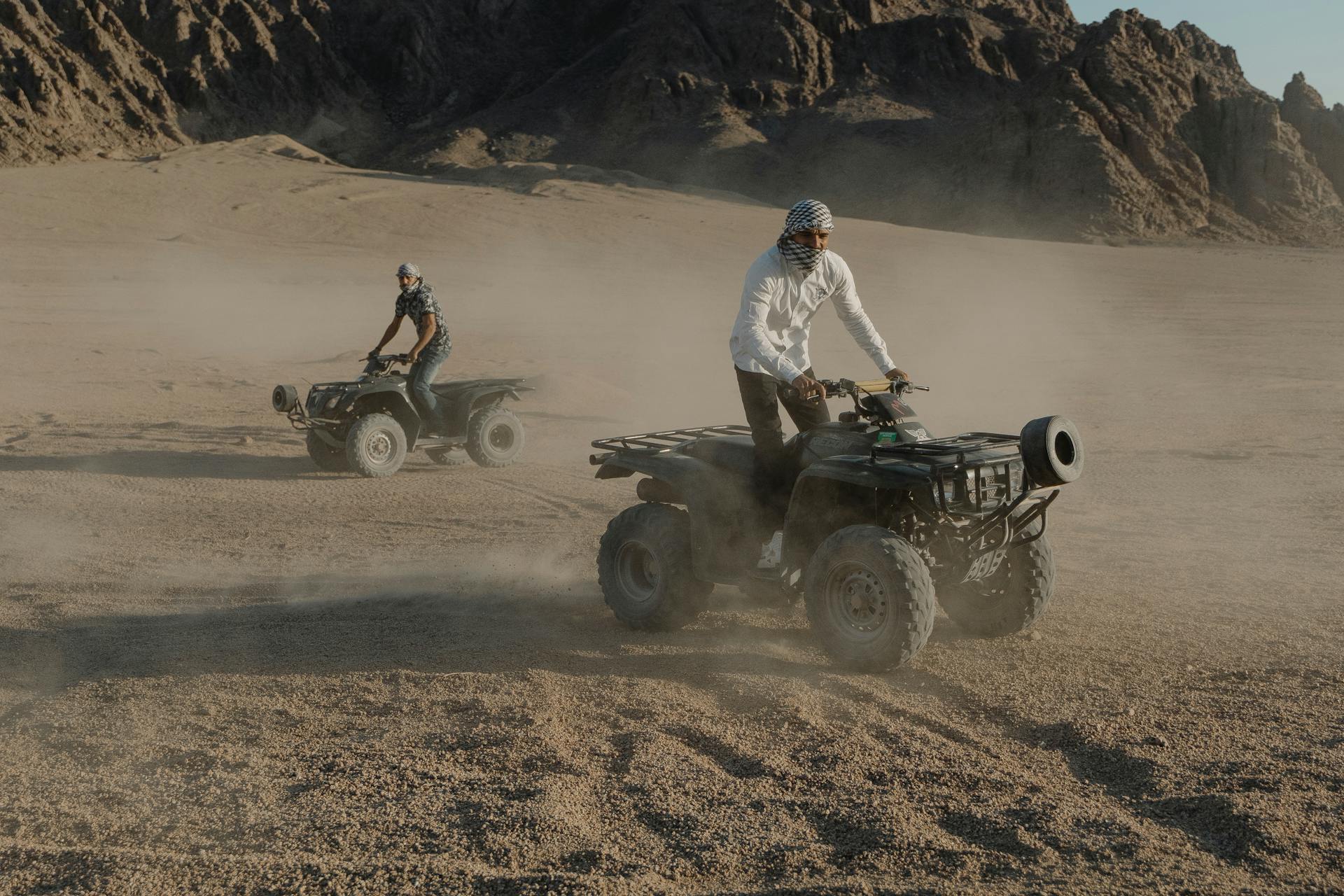 Two men enjoy an exhilarating ATV ride across the dusty desert terrain.