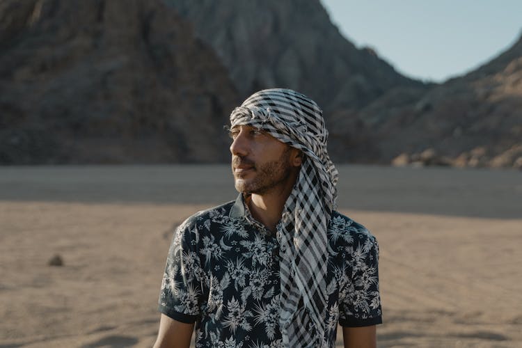 A Man In Printed Shirt And Headscarf On The Desert