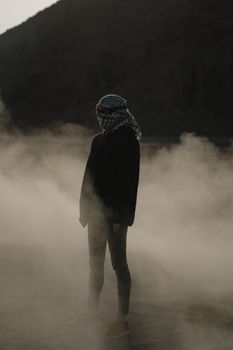 雾蒙蒙的沙漠景观中，灯光下站着一位神秘人物