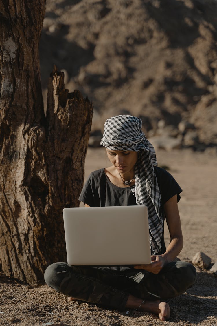 
A Woman Using A Laptop While Sitting On The Ground