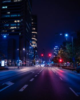 Vivid night scene of Warsaw's illuminated city streets with towering skyscrapers.