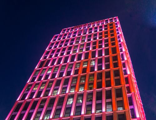 Free Vibrant pink and orange lights illuminate a skyscraper against a night sky. Stock Photo