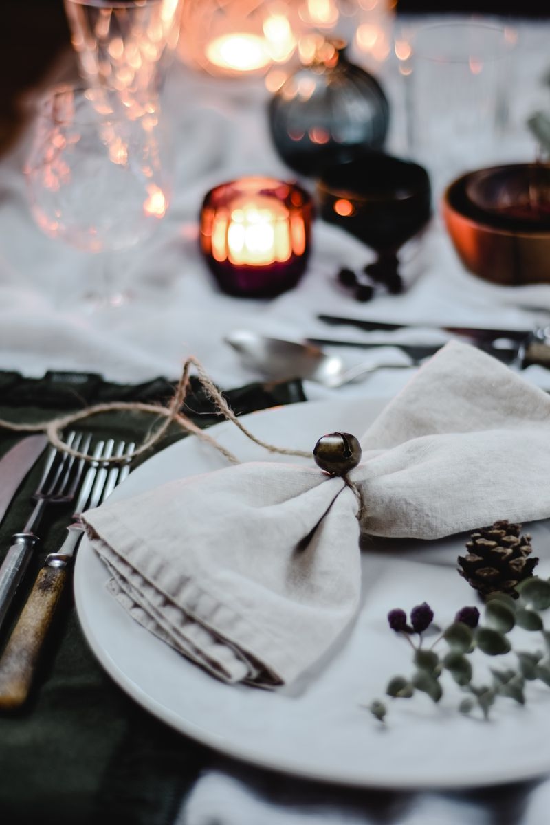 A rustic table setting — candles, linen, worn silverware.