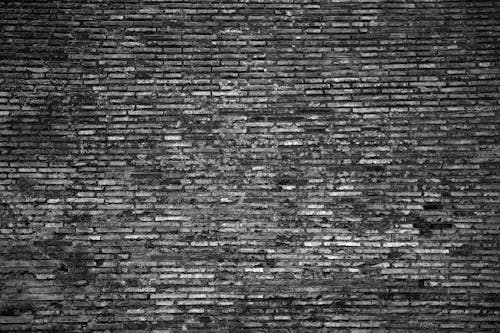 Black and white abstract background of weathered old brick wall texture with cracks and scratches
