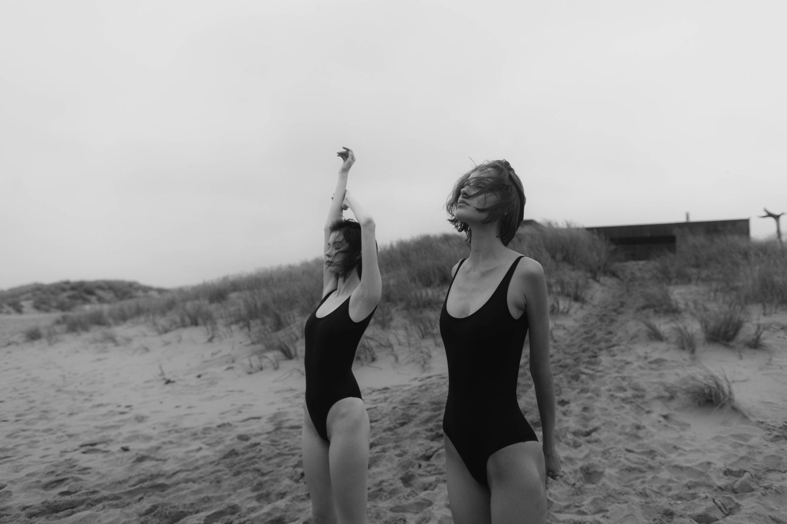 Women in black one-piece swimsuits on the sand — Salt Water, the luxury swimwear edit