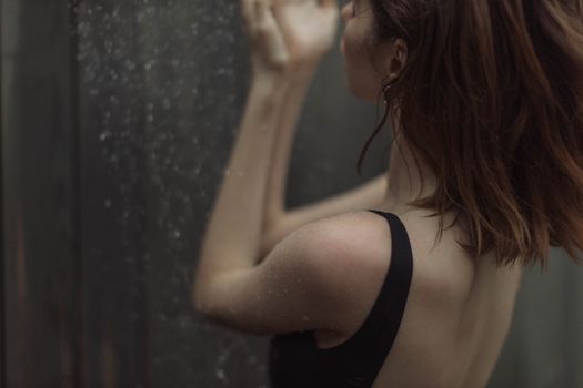 一名穿着泳衣的女子背对镜头，模糊的背景上溅满了水滴