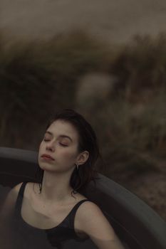 这幅肖像画描绘了一位女子在黄昏时分于户外热水浴缸中放松的场景，画面宁静
