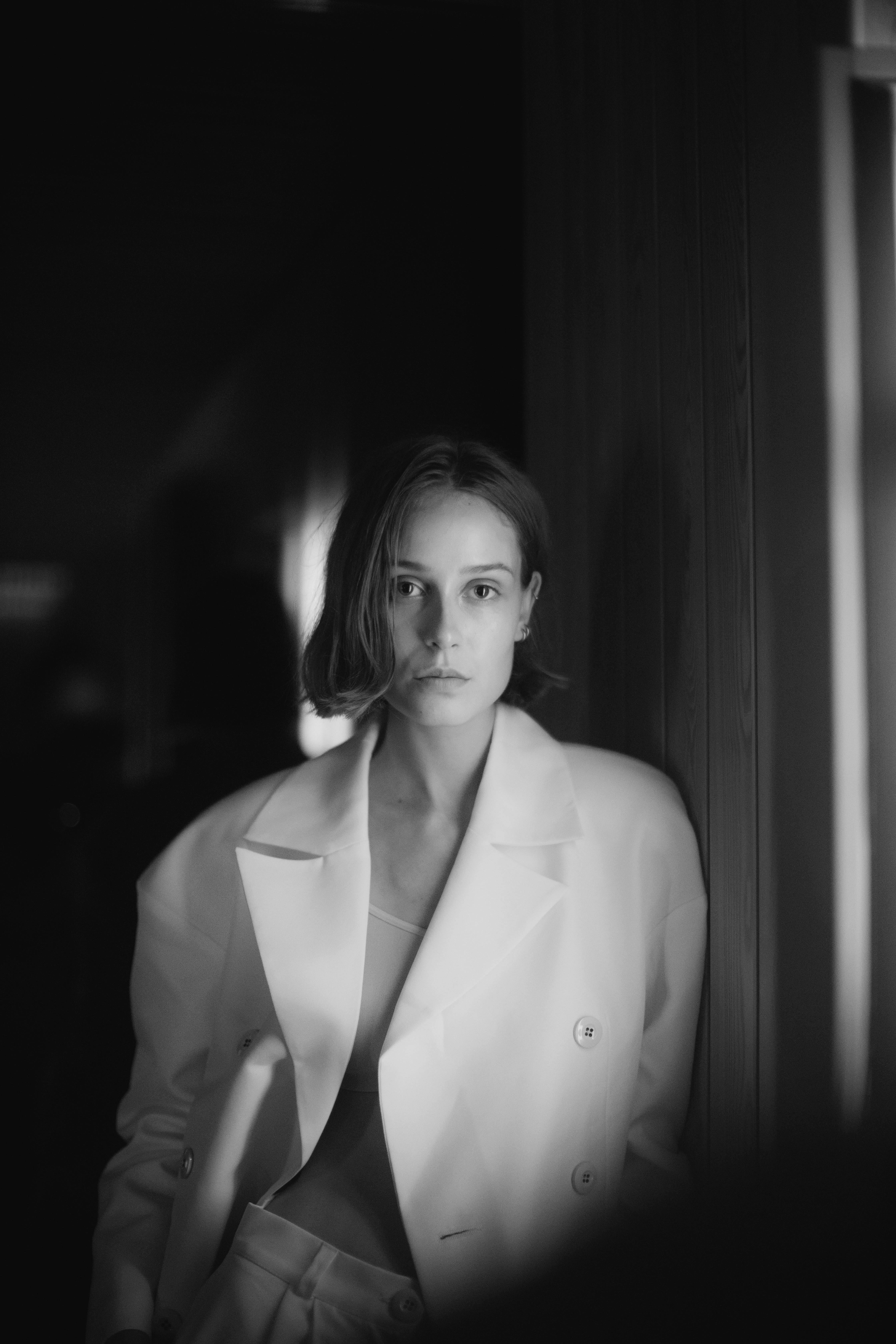 Stylish monochrome portrait of a woman in a white suit indoors.
