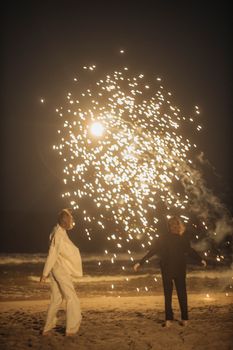 夜晚，两人在海滩欣赏耀眼的烟花表演，为这一刻增添了魔力