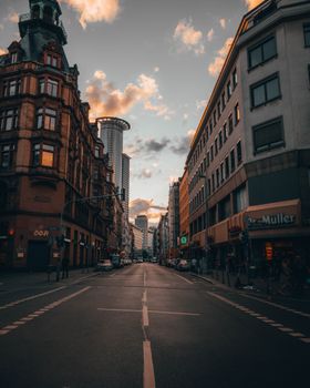 Wide asphalt road between buildings with classic facades and sidewalks in modern city
