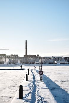 芬兰坦佩雷白雪皑皑的城市景观宁静祥和，冬季河流冰封，工业背景依稀可见