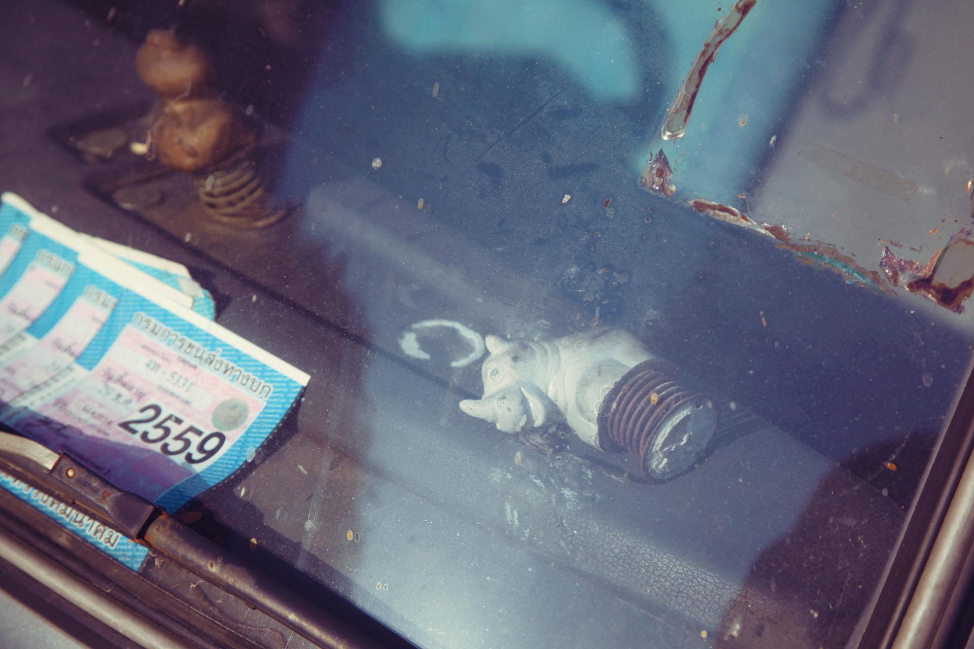 From above through scratched car front window of permit papers and rhinoceros statuette