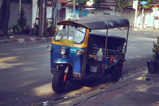 Empty typical tuk tuk motor scooter parked on asphalt roadside in Asian town in daytime