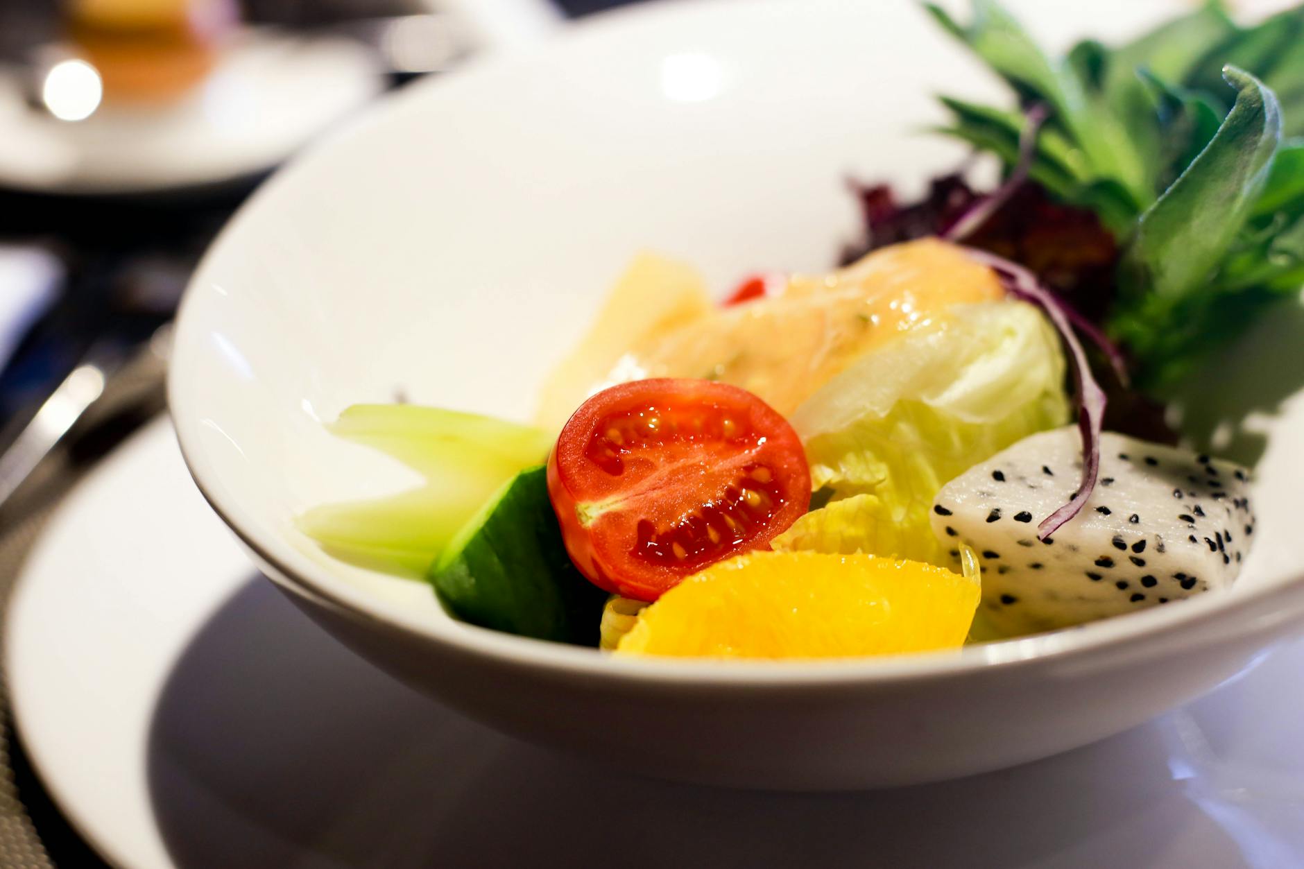 A fresh and colorful salad bowl featuring tomatoes, lettuce, cucumber, and dragon fruit, perfect for a healthy meal.