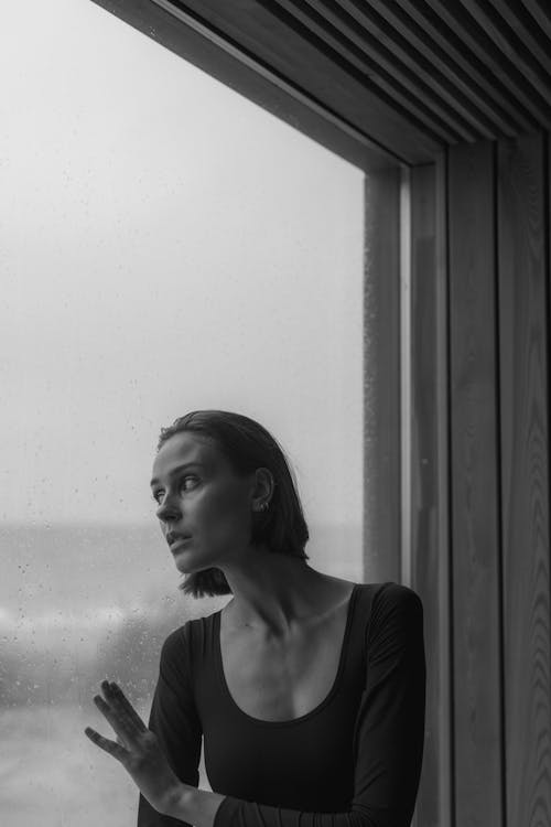 Free Grayscale Photo of a Woman Looking at a Glass Window Stock Photo