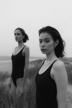 Elegant black and white portrait of two women in swimsuits on a beach.