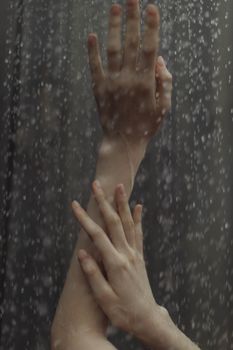 Elegant close-up shot of hands reaching upwards with water droplets in motion.