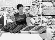 A woman selling a variety of dried fruits at an outdoor market stall, showcasing local produce.