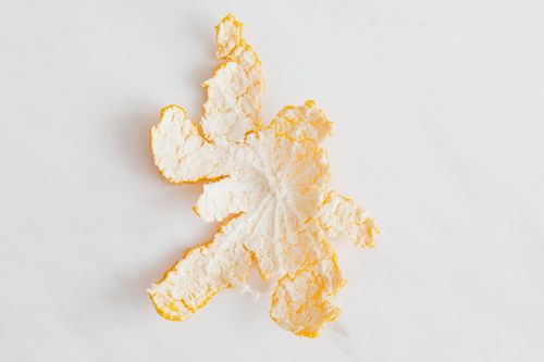 Free Artistic minimalist image of a single orange peel on a white surface. Stock Photo