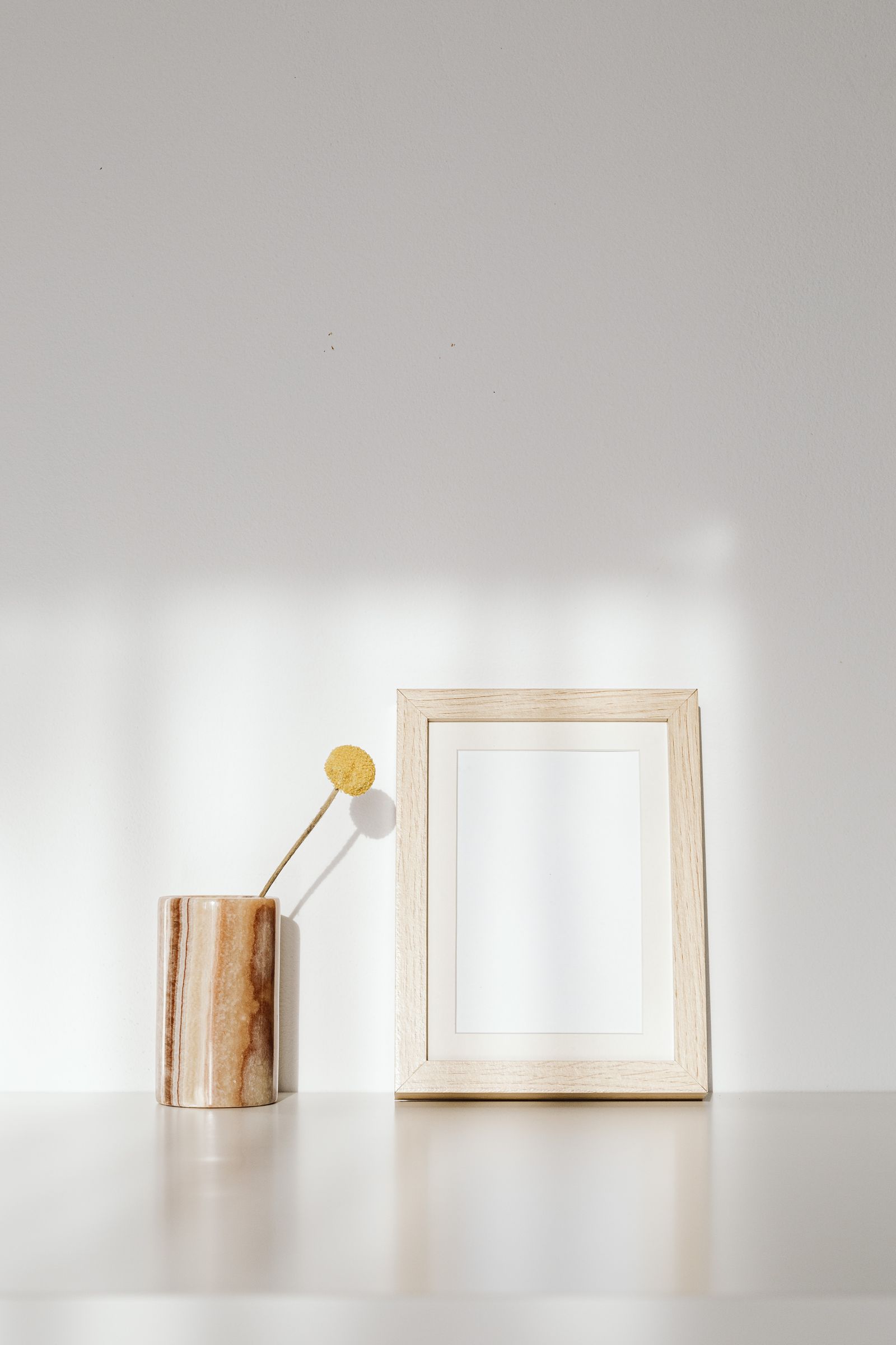 minimalist room design 2026 wooden frame and ceramic vase on white wall natural light