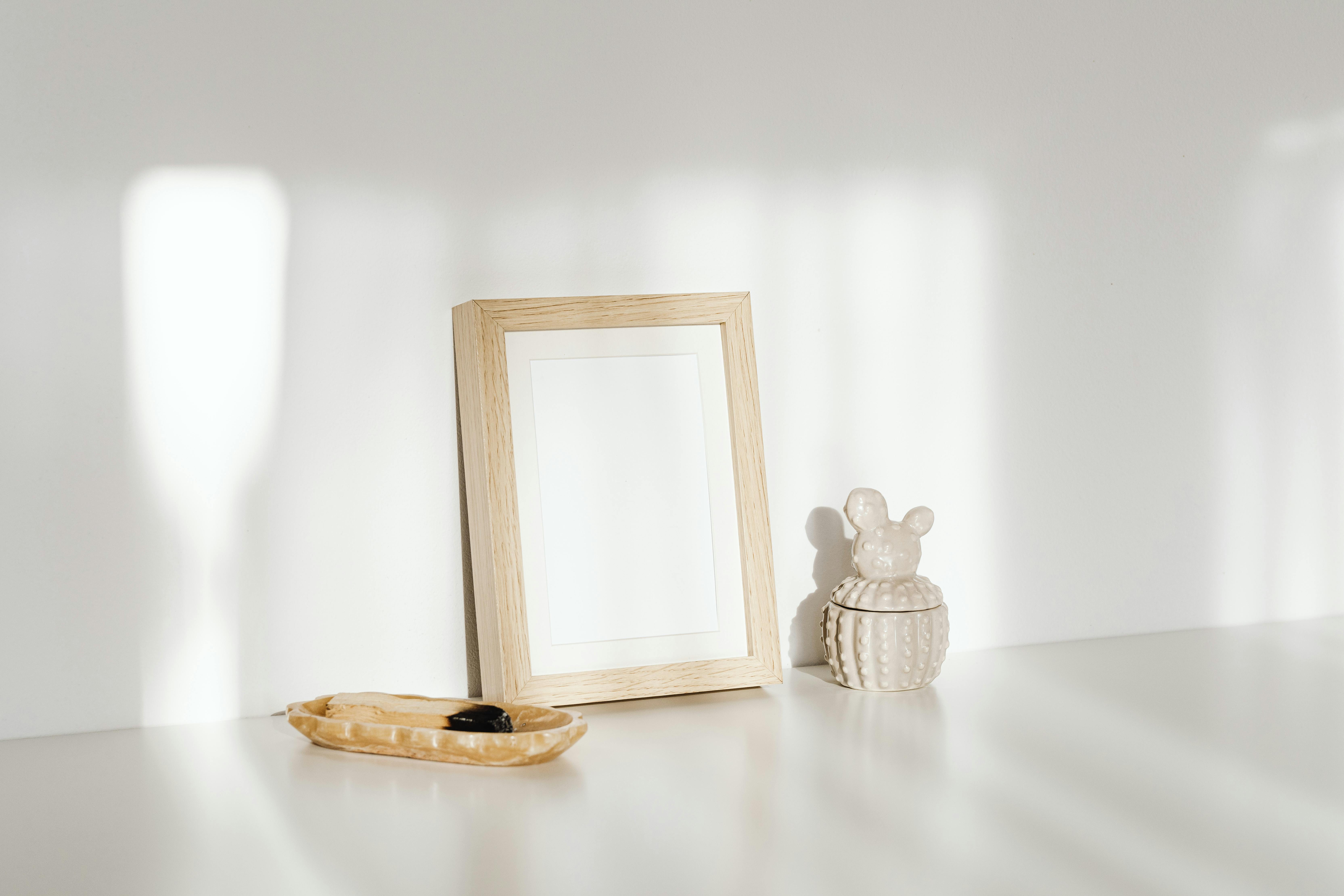 A minimalist setup featuring a wooden frame and ceramic decor on a sunlit surface.