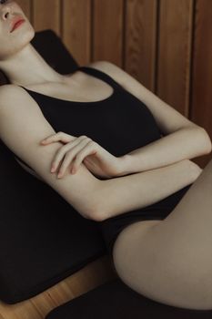一名女子身穿黑色泳衣，在室内摆出宁静优雅的姿势躺着