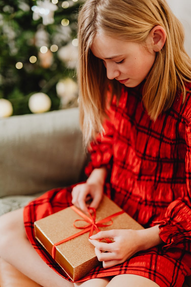 Blonde Girl Sitting In A Couch Opening A Gift Box 