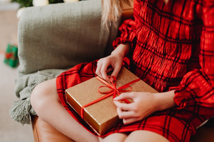 A Person Sitting Opening A Gift 