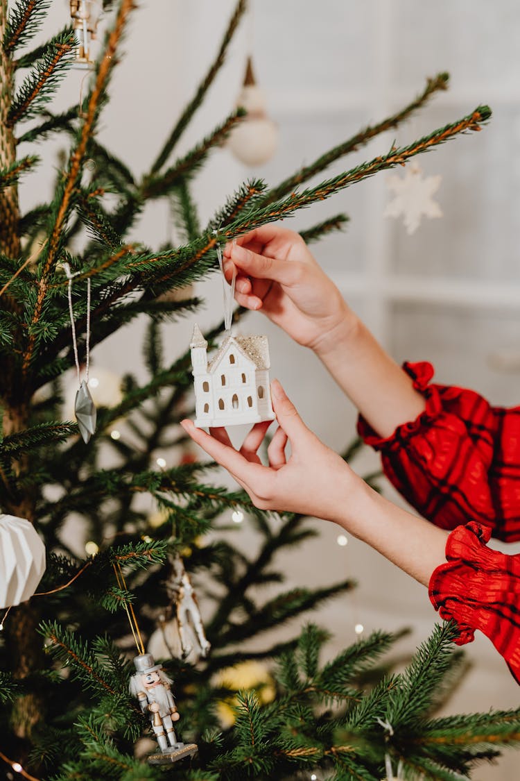 Woman Hanging An Ornament On A Christmas Tree