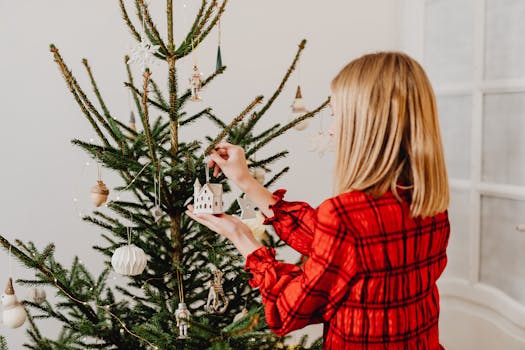 Woman in red dress hanging ornaments on a Christmas tree indoors.