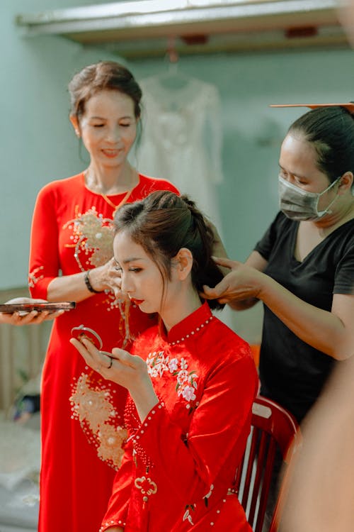 Free Woman in a Traditional Chinese Red Dress Getting Her Hair Styled Stock Photo