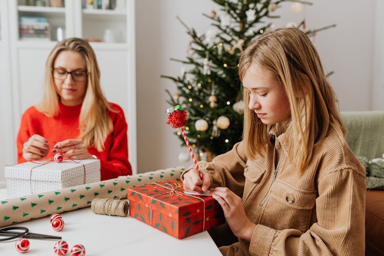 Mother And Daughter Wrapping Christmas Gifts Together