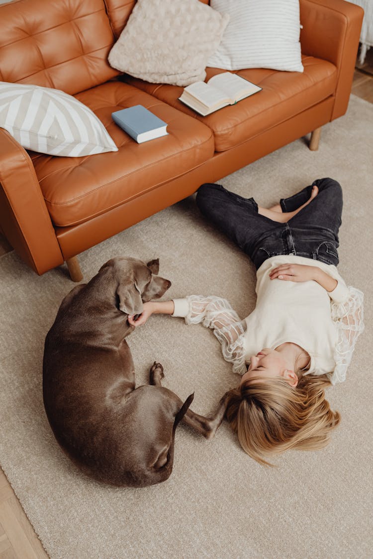 Young Girl Lying On A Carpet With A Dog