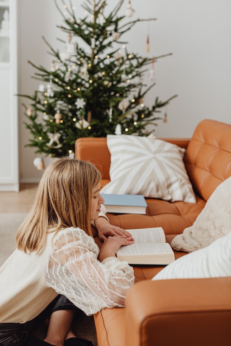 Girl Reading Book On A Sofa During Christmas