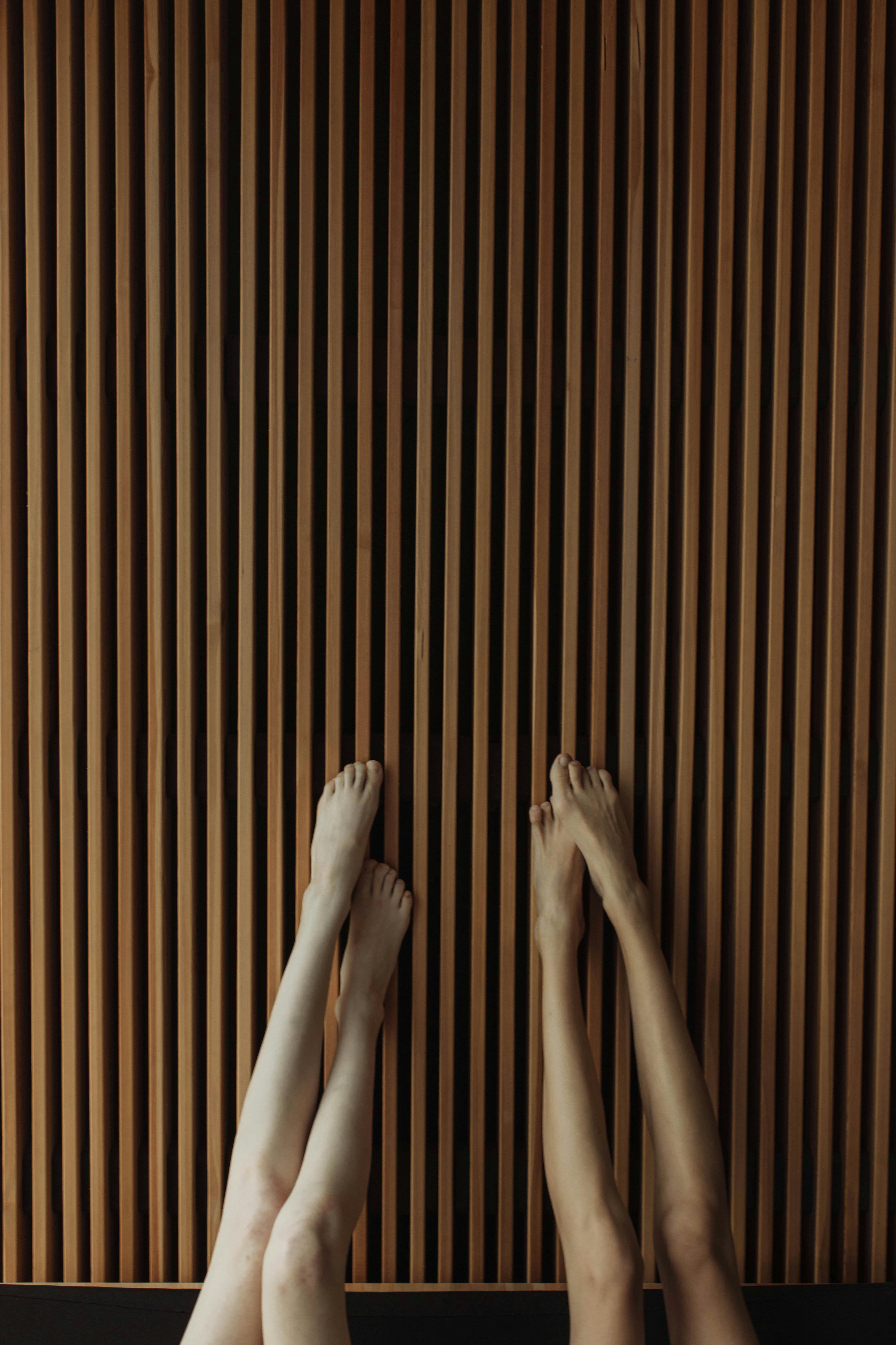person s feet on the wooden wall