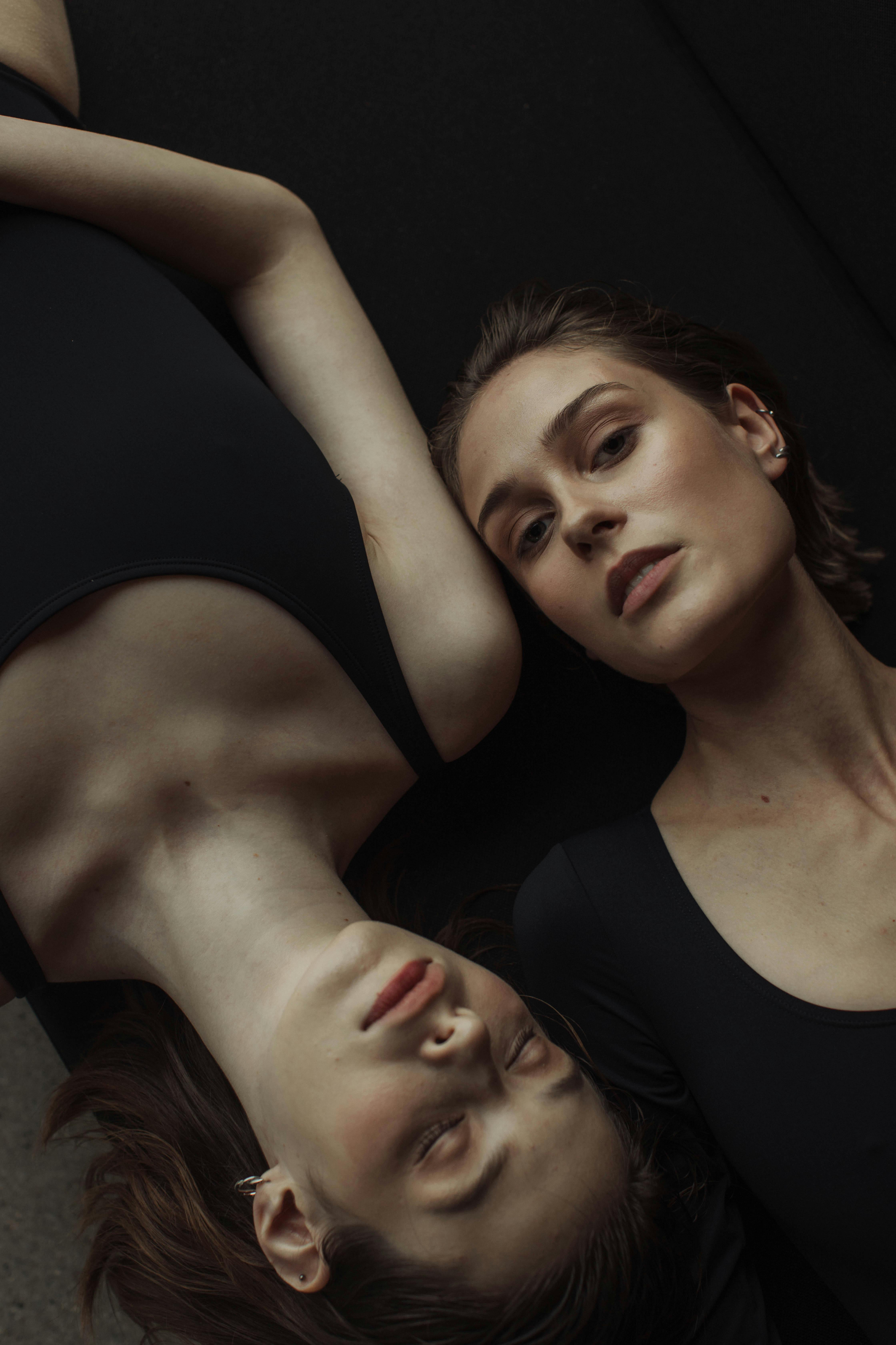 Moody studio portrait of two women in black tops creating a dramatic composition.