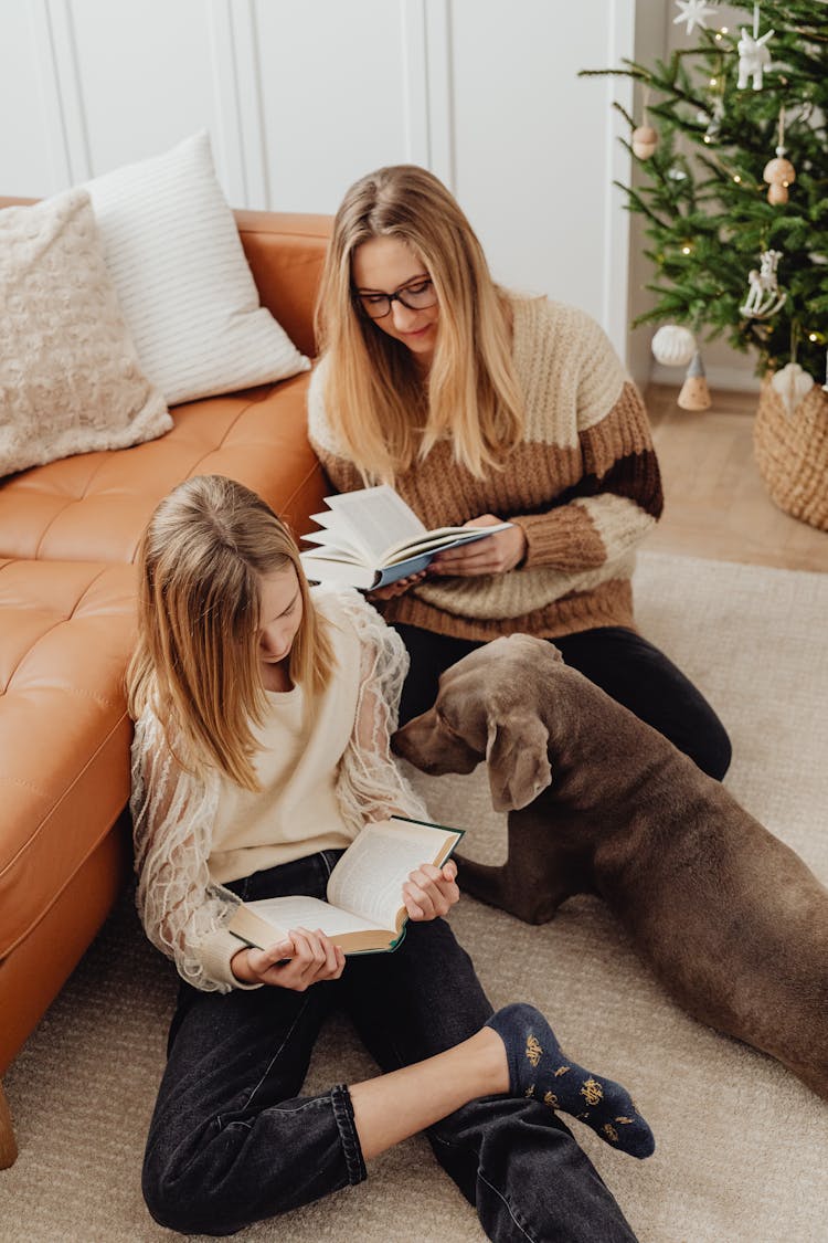 Mother And Daughter Reading On A Floor Next To A Dog 