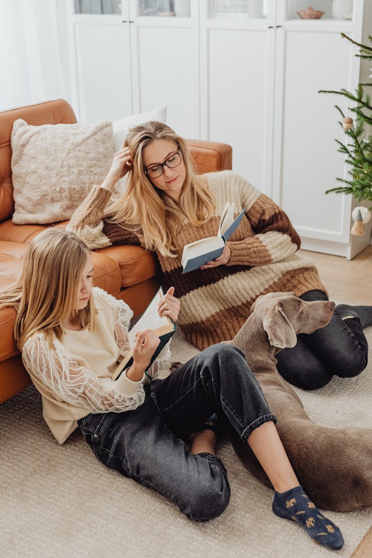 Mother And Daughter Reading Books With Their Dog 