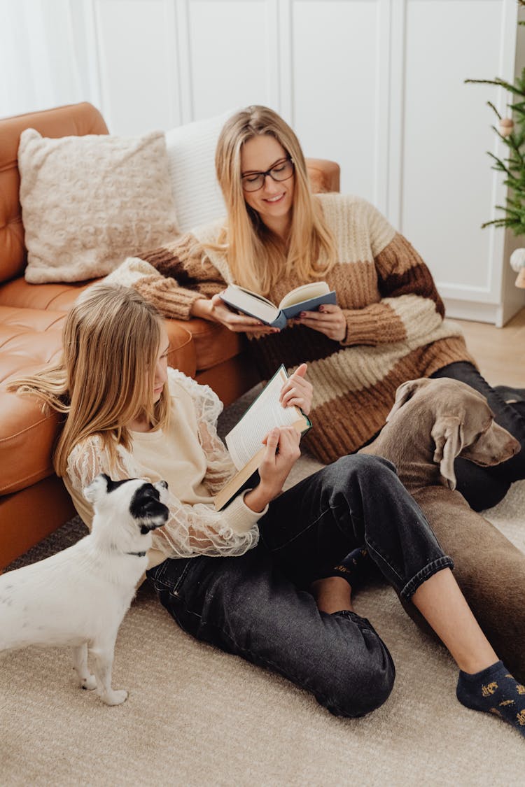 Mother And Daughter Reading Books Surrounded By Dogs