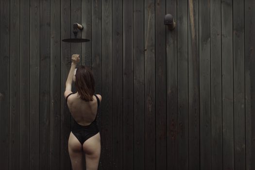 一位女士以木板为背景，在户外享受清爽的淋浴